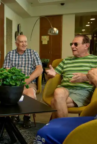 מועדון הספר - שני גברים מהווים חלק ממעגל היושבים סביב שולחן, על השולחן עציץ