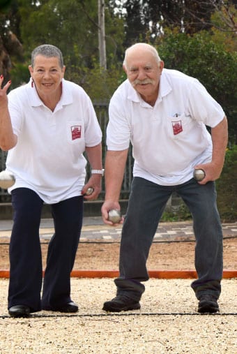 גבר ואישה בחולצות לבנות משחקים בפטאנק (משחק כדור)