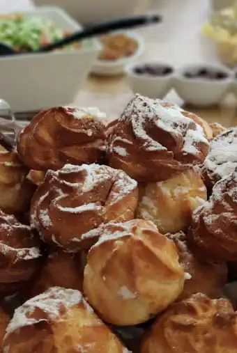 מסעדה - צלחת מלאה בפחזניות מאחוריה מונחים עוד ארבעה קערות , אחת גדולה עם סלט ועוד 3 קטנות יותר .