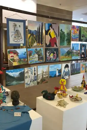 גלריה של ציורים תלויה על קיר רשת על הפודיום מונחים יצירות עבודת יד מסוגים שונים