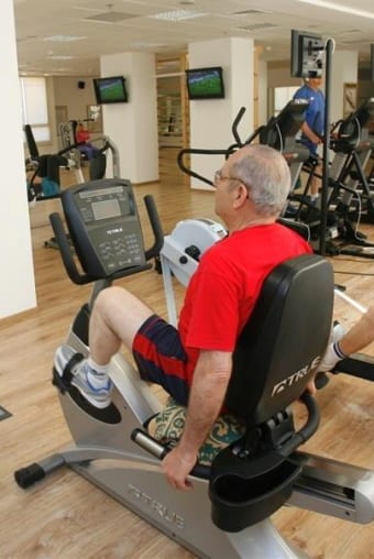 פעילות ספורט אדם יושב על מכשיר כושר - אופניים בחדר הכושר שבאחוזה