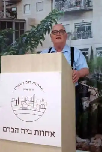 אדם עומד ליד פודיום הרצאות ומרצה בחצר אחוזת בית הכרם