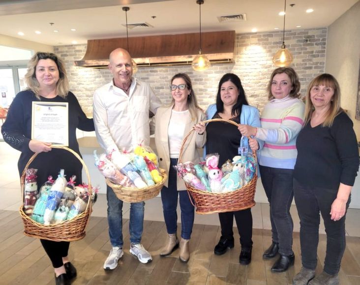 דיירי אחוזת ראשונים מחזיקות סלסלאות עם בובות שסרגו לילדים מאושפזים