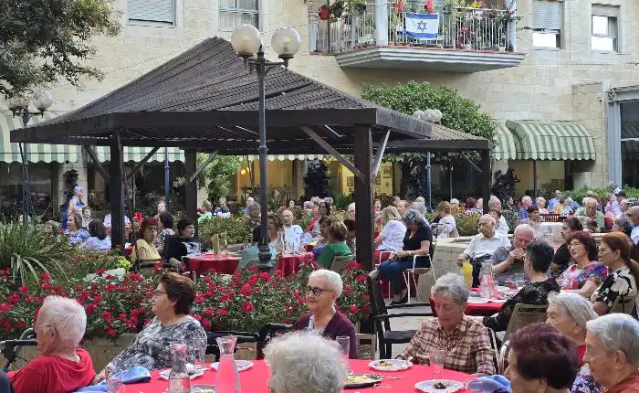 דיירי אחוזת רובינשטיין יושבים סביב שולחנות בארוע